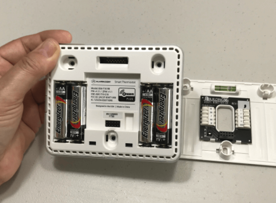 open thermostat showing batteries inside to check as an easy DIY fix when your HVAC system stops working