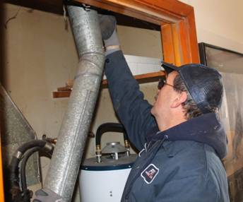 Skilled HVAC technician working on pipes from an old furnace in a Wichita home